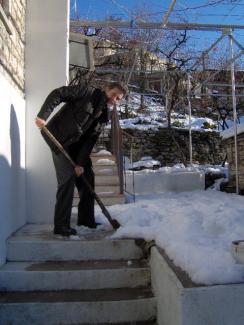Ο Γιώργος Κάλης καθαρίζει την αυλή του από το χιόνι. 